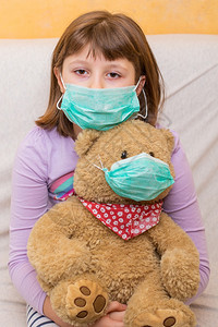 新冠概念年轻女孩用医疗面具巨大一只泰迪熊图片