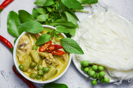 汤碗上的泰国菜绿咖喱鸡和面碗上配有蔬菜成份的米面图片