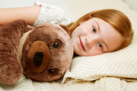 躺在床上的小女孩抱泰迪熊图片