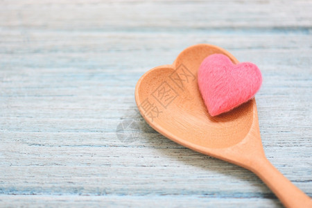 木勺和桌背景上的粉红心顶视咖啡勺心脏形状爱健康或烹饪概念图片