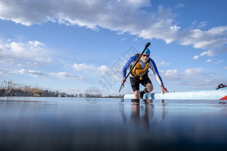 高职男护甲手站在一个平静湖岸的滑板上低角度视图形成行动摄影机娱乐健身和培训概念图片