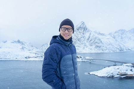 亚洲游客站在山上前往挪威欧洲的洛福滕群岛白雪山冬季自然景观旅行和徒步冒险图片