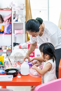 亚洲女孩玩具和彩色纸在家里客厅上艺术课在家里上学而城市封锁是因为世界各地以四胞胎妈为老师图片