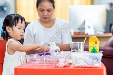 亚洲女孩玩具和彩色纸在家里客厅上艺术课在家里上学而城市封锁是因为世界各地以四胞胎妈为老师图片