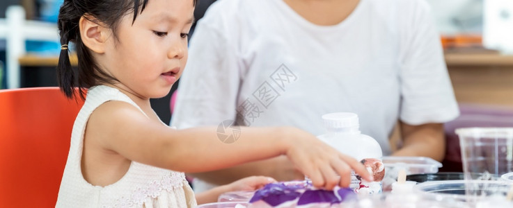 全景主义的亚裔女孩在家中上客厅的艺术课时弹着多彩的纸质文章图片