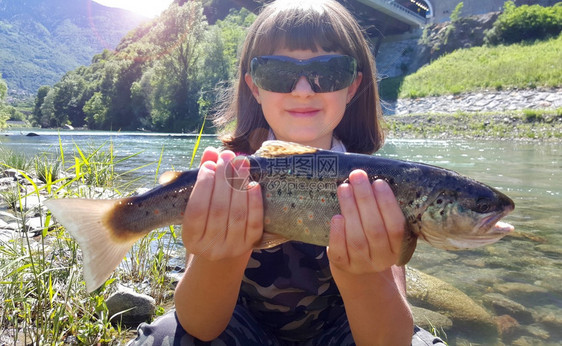 年轻女孩在河里钓鳟鱼图片