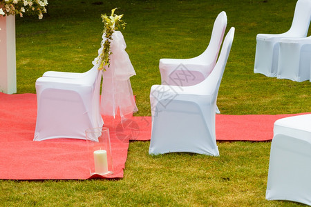 红毯秀许多张白色优雅的婚礼椅子上面有绿色草地和长的红毯外门拍摄许多张白色优雅的婚礼椅子上面有白色优雅的纱背景