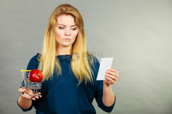 持有水果购物篮的忧虑妇女看着账单收据害怕价格暴涨图片