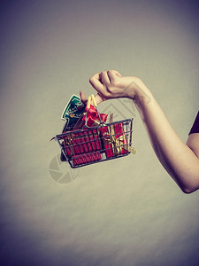 圣诞节季节销售冬庆祝活动概念妇女手拿着购物车篮子里面有小圣诞树和礼物背景图片