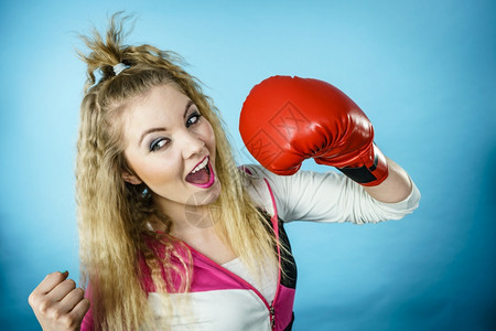 穿着红手套的有趣金发女孩拳击手 玩运动演播室 蓝射击穿着红手套的有趣女孩玩运动拳击背景图片