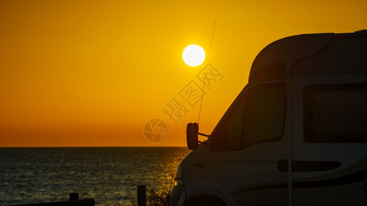 日出时在西班牙海滩度假旅游的露营房车图片
