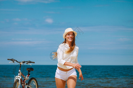 骑自行车的草帽女青年在海滩上奔跑图片