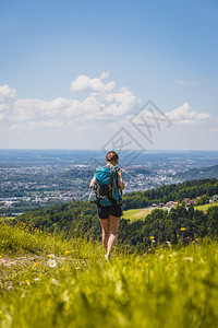 徒步旅行的体育女运动员站在草地上享受远城风景图片