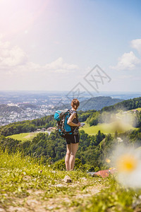 徒步旅行的体育女运动员站在草地上享受远城风景图片