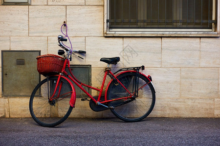 在意大利里米尼的墙附近带篮子的红色自行车图片
