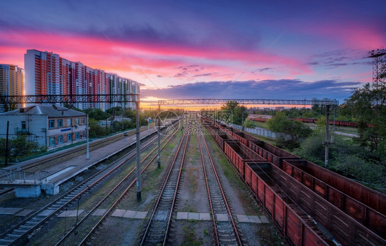 火车站的空中景象夏季日落时有多彩的货运列车铁路的顶端景象重工业火车的横向风景火车建筑物黄昏时有粉色云的天空运输图片