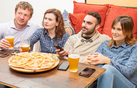 一群朋友在喝啤酒吃比萨饼在家休息时聊天和微笑图片