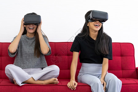 两个亚洲美女在玩VR视频游戏时微笑在客厅体验隔离期间良好的心理健康游戏技术休闲和心理健康概念图片