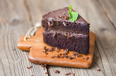 餐桌上的蛋糕巧克力甜点木制切板上一块蛋糕片配巧克力和薄荷叶图片