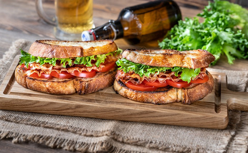 木板上配有培根生菜和番茄的BLT三明治图片