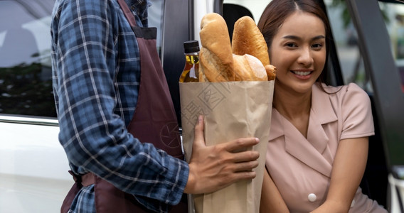 送货人员在超市的车道服务站向亚洲女顾客提供杂货包驱动器是流行的服务在科罗纳新冠流行19之后是新常态图片