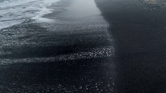 海洋滩上湿黑色火山砂的近抽象图像背景图片