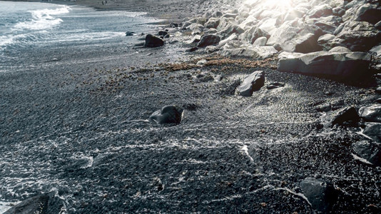 黑色火山海沙滩和蓝色浪上闪耀着明日的海景黑色火山海沙滩和蓝色洋浪上闪耀着明日的海景图片