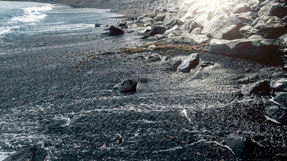 黑色火山海沙滩和蓝色浪上闪耀着明日的海景黑色火山海沙滩和蓝色洋浪上闪耀着明日的海景图片