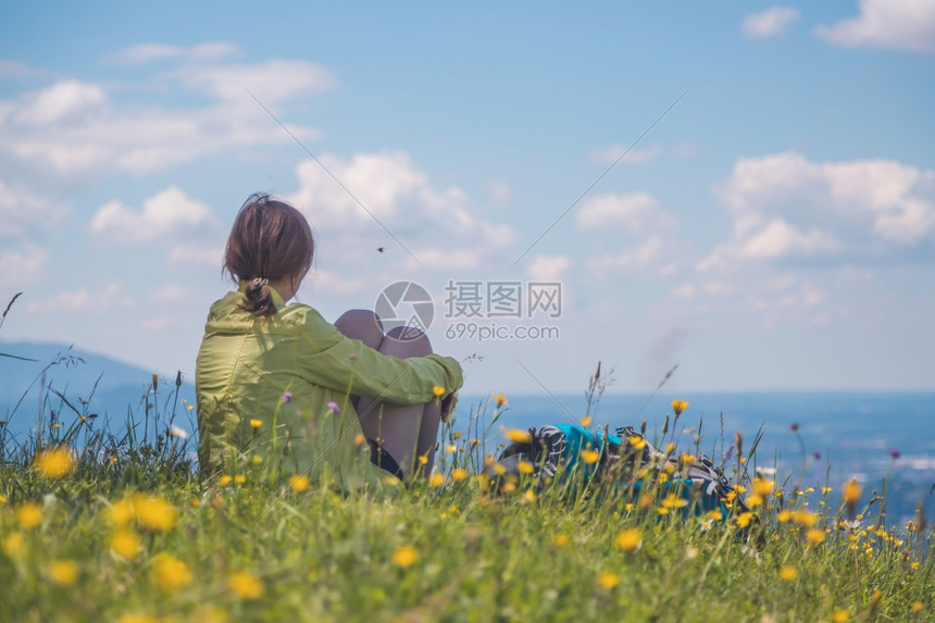 徒步旅行的女运动员坐在草地上享受风景图片