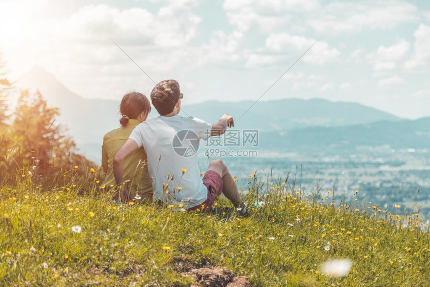 来远足旅行的夫妇坐在草地上欣赏风景图片