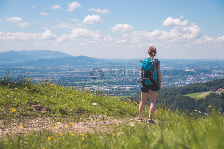 徒步旅行的体育女运动员站在草地上享受远城风景图片