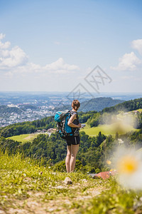 徒步旅行的体育女运动员站在草地上享受远城风景图片