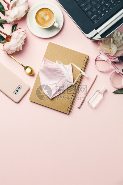 办公室桌平板面博客工作空间模型上面有咖啡计算机花朵面罩清洁剂和粉红色背景的女配件图片