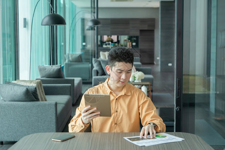 快乐笑的年轻亚洲商人使用平板电脑商业文件的人在家里的会议室线工作技术设备概念图片