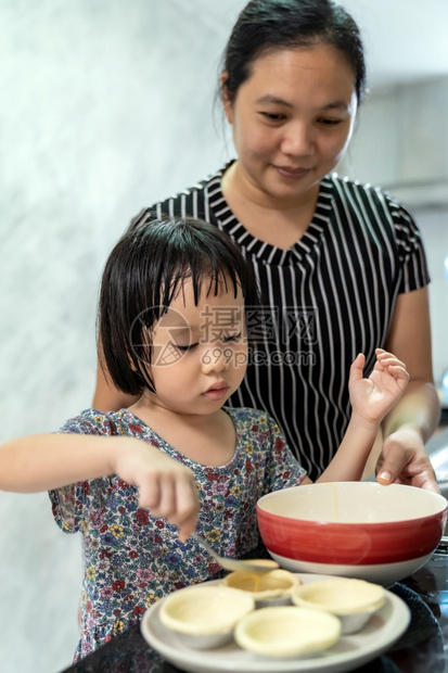 亚洲女孩与母亲一起做鸡蛋煎饼面包店儿童家务使发挥行政功能图片