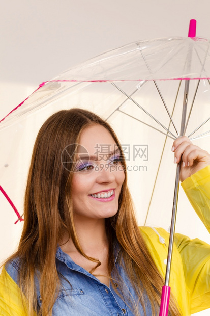 身着防水黄色大衣站在雨伞下玩得开心的雨中微笑女孩气象预报和天季节概念身着雨伞下防水大衣的妇女图片