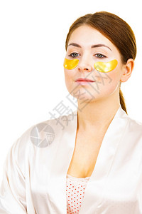 年轻女在白眼上涂金色的椰子膜面罩除去皱纹和黑圈女孩照顾眼睛周围的微妙皮肤美容治疗女在眼下涂上金色的斑点女在眼睛下涂上金色的斑点女图片