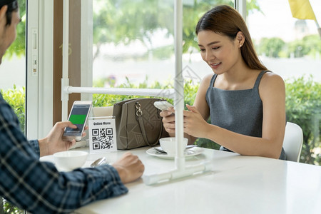 亚洲客户扫描QR代码在线菜单客户坐在社会偏僻的桌子上以适应在餐厅里流行的冠状新冠virus新冠19后的新正常生活方式图片