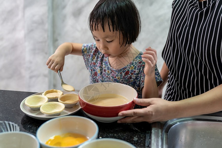 亚洲女孩与母亲一起做鸡蛋煎饼面包店儿童家务使发挥行政功能图片