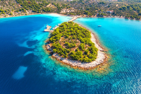 克罗地亚摩尔特岛夏季日出时海湾中美观小岛的空景象透明蓝水绿树山地沙滩船只和游艇的空中景象图片