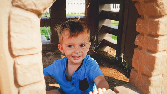 与玩具塑料屋一起在公园玩耍的可爱小男孩肖像图片