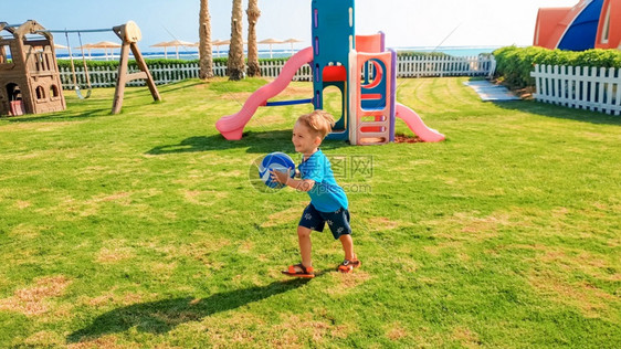 笑快乐的男孩手握着橄榄球在公园儿童游乐场上跑动图片