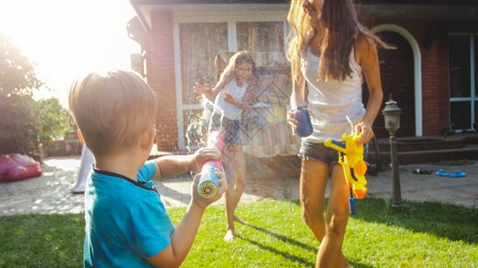 泼水的男孩3岁的幼儿男孩在家庭后院用玩具泼水;夏季儿童在户外玩耍和乐;3岁的幼儿男孩在家庭后院用塑料玩具泼水;夏季儿童在户外玩耍和乐。背景