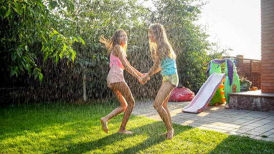 喜笑儿童穿着湿衣服在花园的温暖雨下跳舞家庭夏季在户外玩喜笑儿童穿着湿衣服在花园的温暖雨中跳舞家庭夏季在户外玩乐图片
