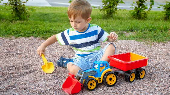 拿铲子挖沙填满玩具卡车的男孩图片