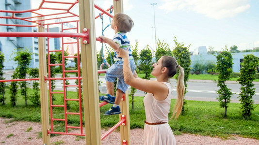 母亲在公园游乐场上扶儿子爬梯子图片