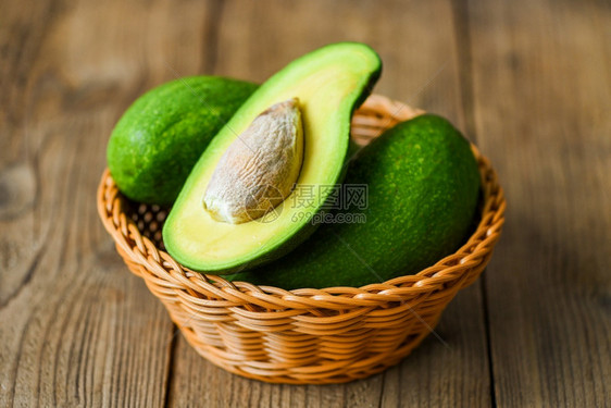 Avocado在木制桌子水果健康食品概念上将一半切成篮子图片