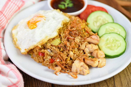 NasiGoreng炒饭鸡白盘和酱汁上加鸡蛋番茄黄瓜和Ayam印地安尼西亚食品图片