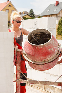 在房屋建筑工地使用红水泥混凝土搅拌机的强力女工图片