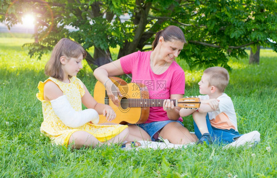 妈和她两个孩子在公园弹吉他放松图片